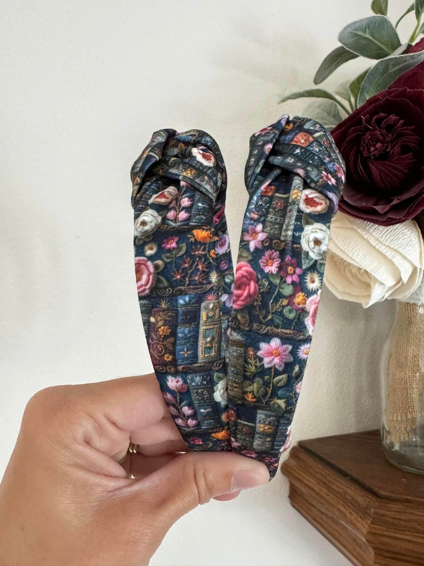 Enchanted Books Top Knot Headband, Step into a storybook world with our Enchanted Books Top Knot Headband. Featuring a darker floral print inspired by classic library tales, this low top knot headband adds a whimsical, Beauty and the Beast–inspired charm